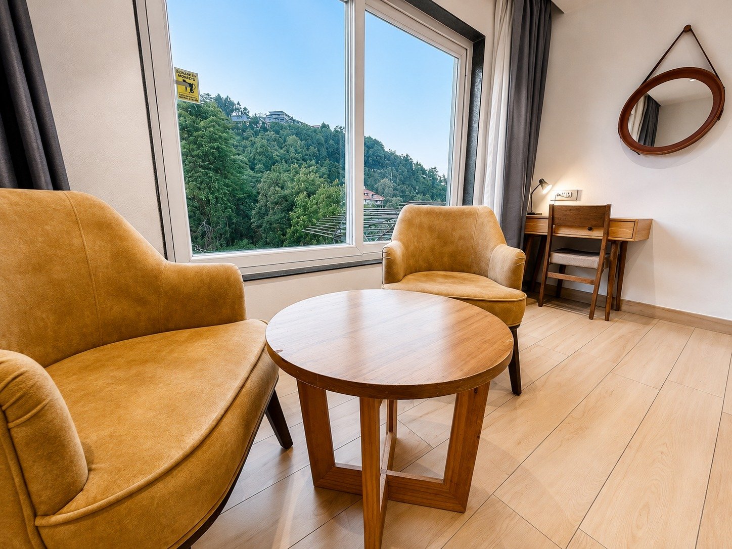Sitting area with armchairs beside a window looking out to green hills